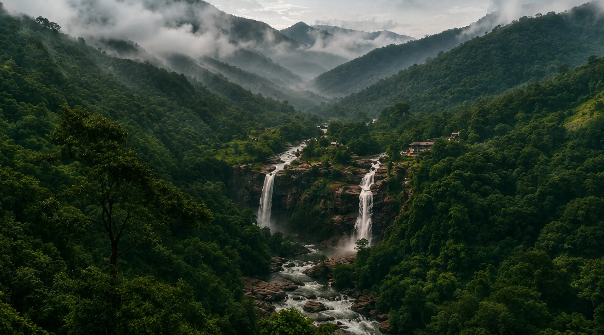 Twin waterfalls cascading through the misted, forested valley of the Pothigai hills